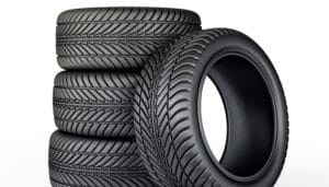Tires stacked on top of one another. Three tires are stacked vertically, and the fourth is leaning against them.